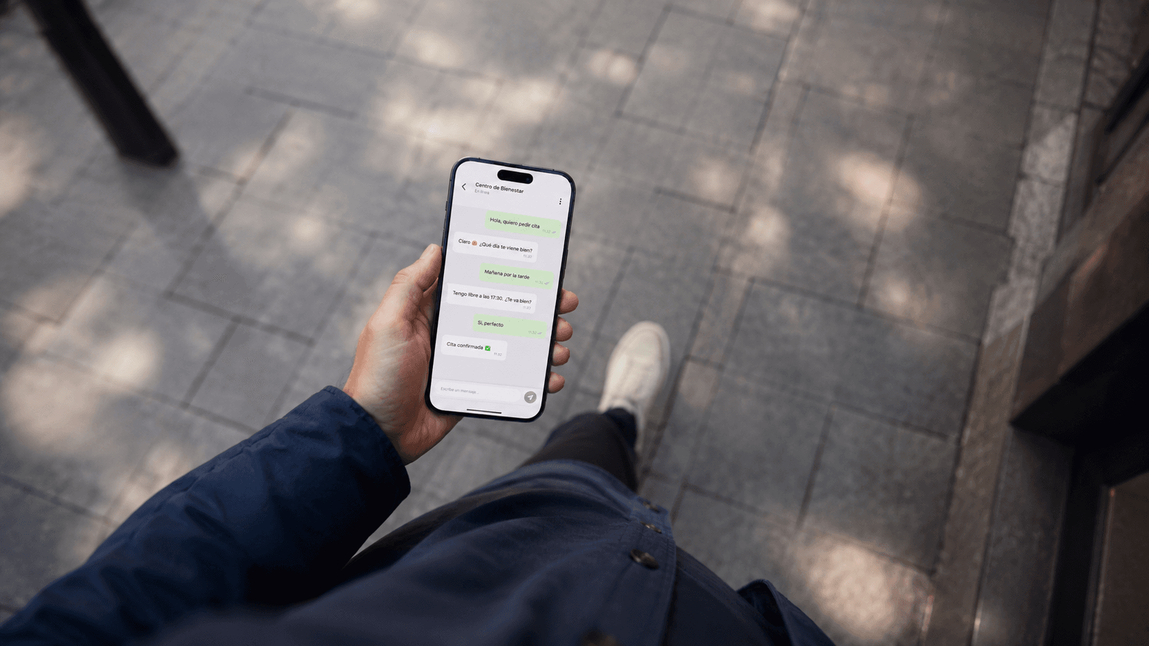 Mano sujetando un móvil con una conversación de reserva por WhatsApp